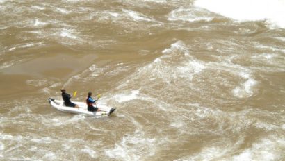 Two paddlers float through Grand Canyon's rapids in an inflatable kayak