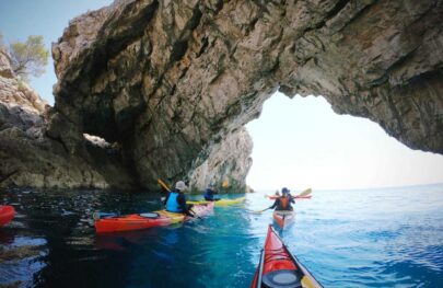 Sea kayakers paddle under an arch near Croatia