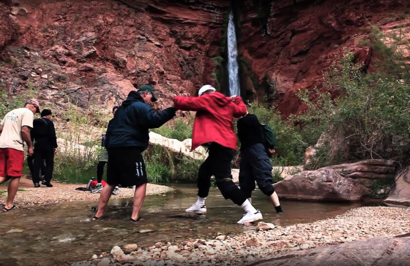Video still of guides helping guest cross a small side creek in Grand Canyon
