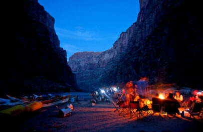 Night time in Grand Canyon on an OARS Dories trip with lights in kitchen and a camp fire