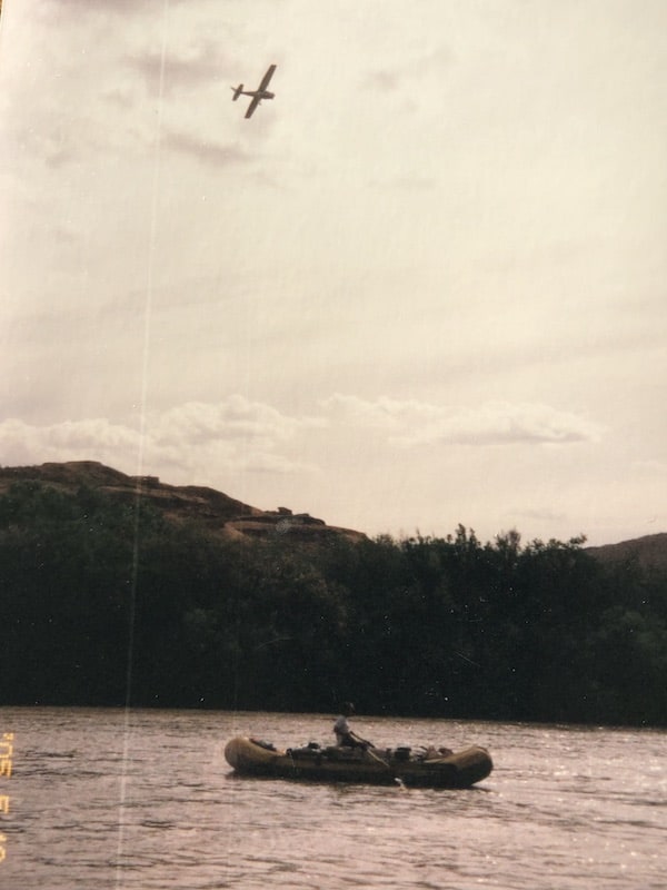 Airplane flying over a raft, preparing to drop bag