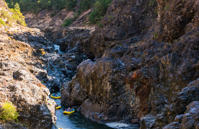 Rafts and inflatable kayaks maneuver through a rocky canyon on Oregon's Rogue River