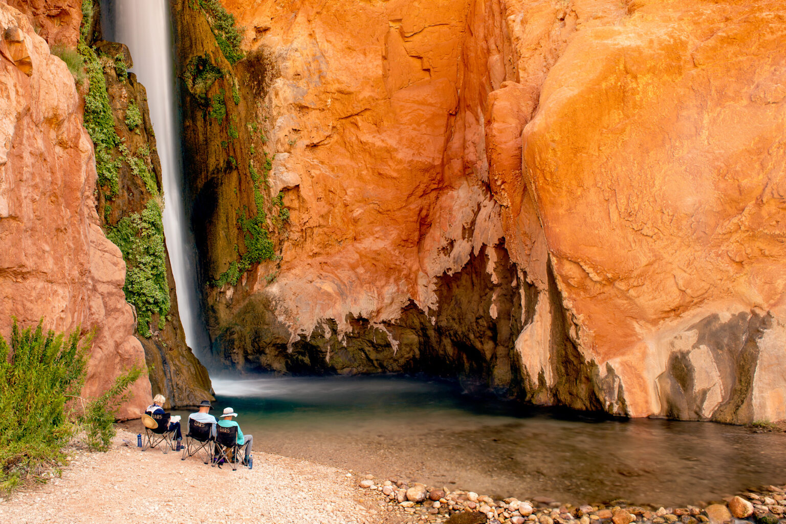 Guests relax and read at foot of Deer Creek Falls in Grand Canyon
