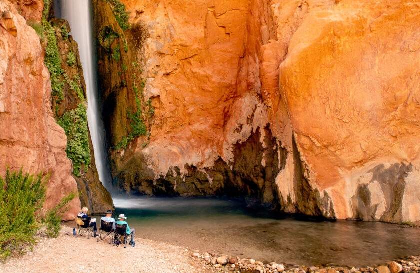 Guests relax and read at foot of Deer Creek Falls in Grand Canyon