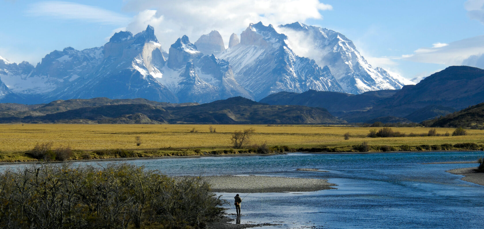 Patagonia's Cerro Torre in the distance with a fly fisherman in the foreground.