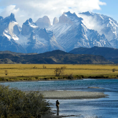 Patagonia's Cerro Torre in the distance with a fly fisherman in the foreground.