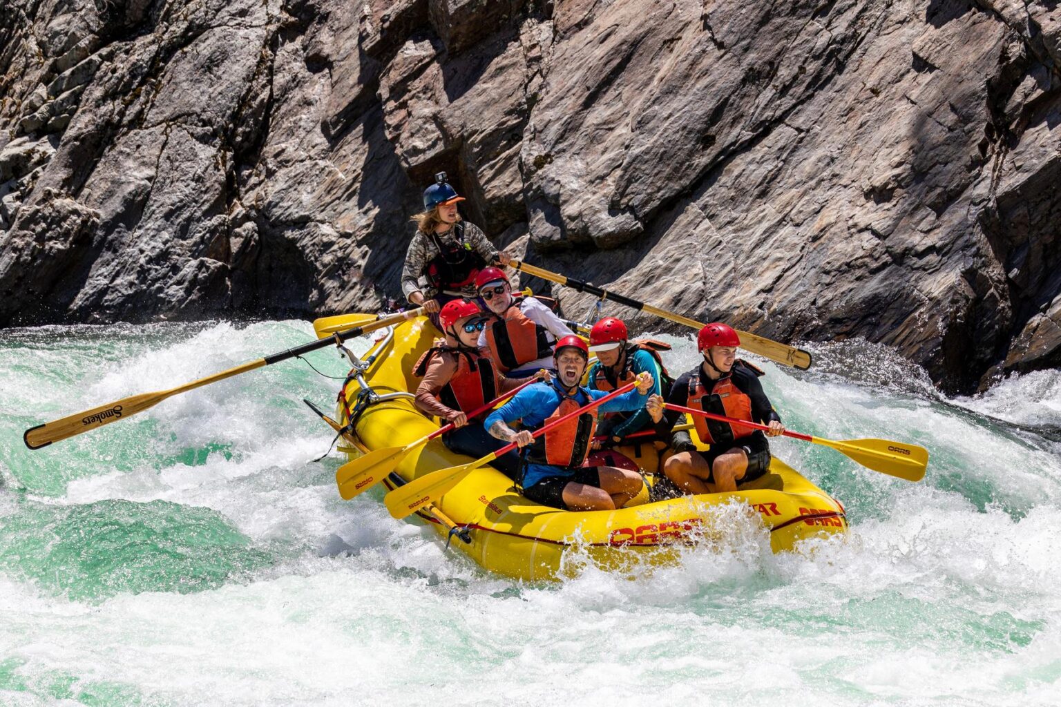 A group of rafters paddling through a rapid on the Tuolumne River.