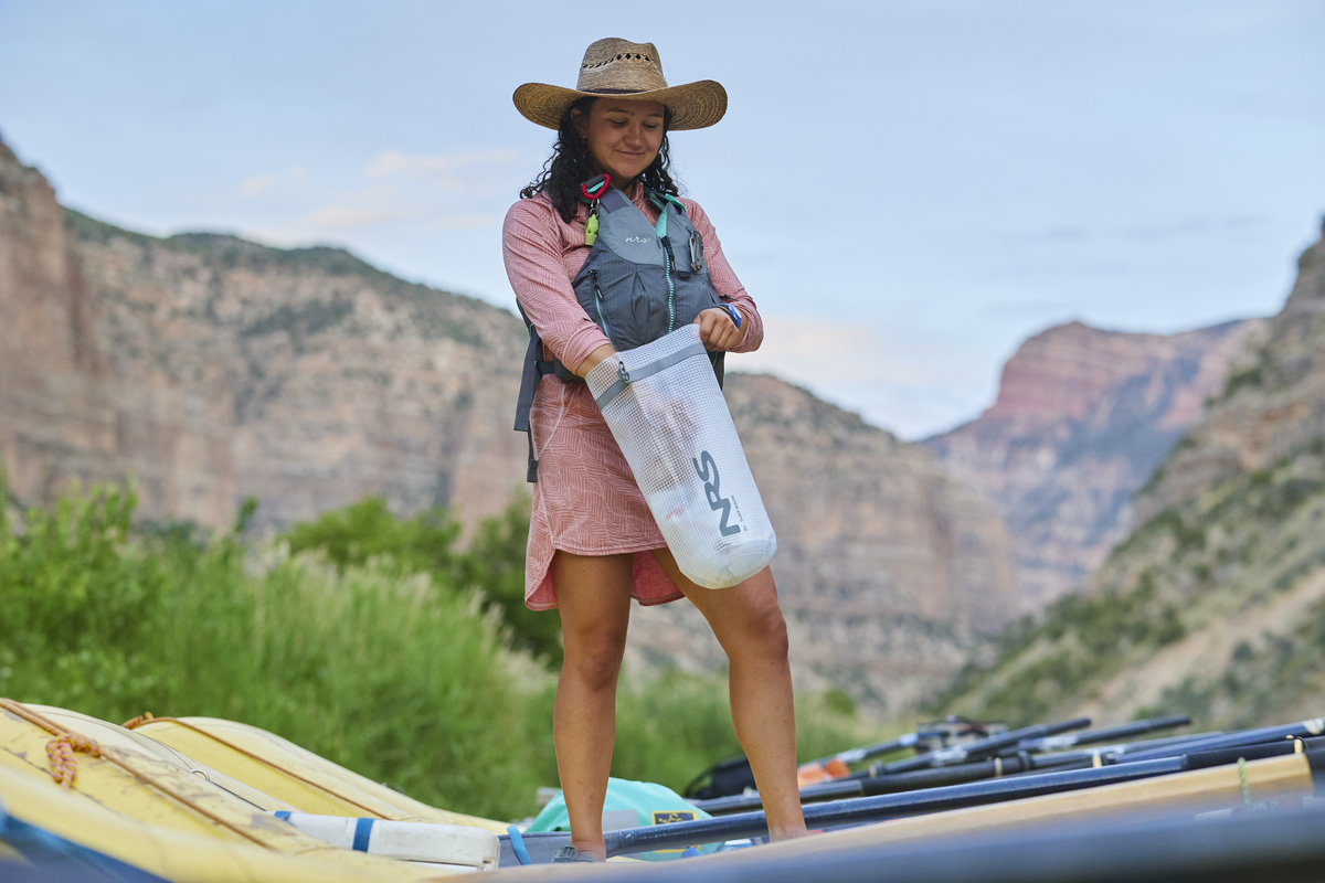 A woman packs a small dry bag during an OARS rafting trip