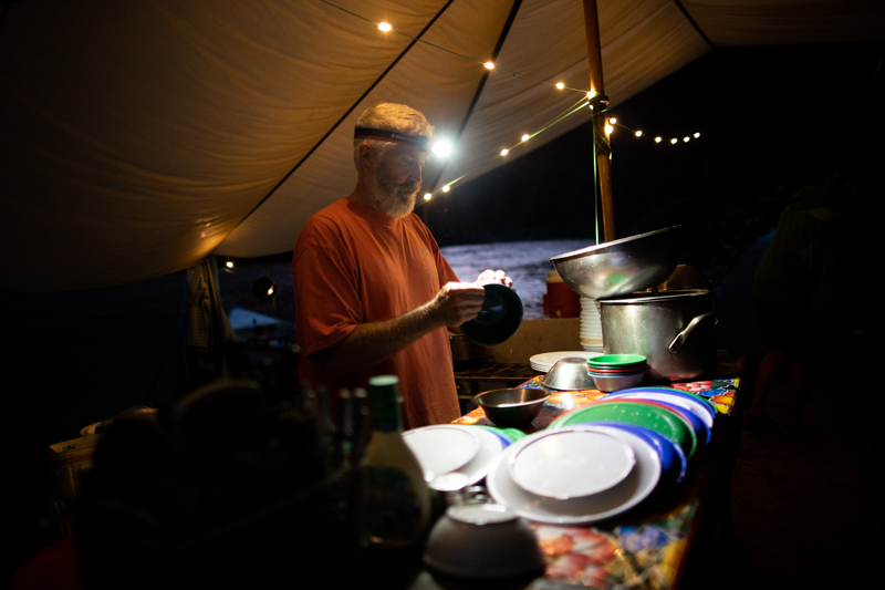 An OARS guide does dishes in the dark on a Grand Canyon rafting trip