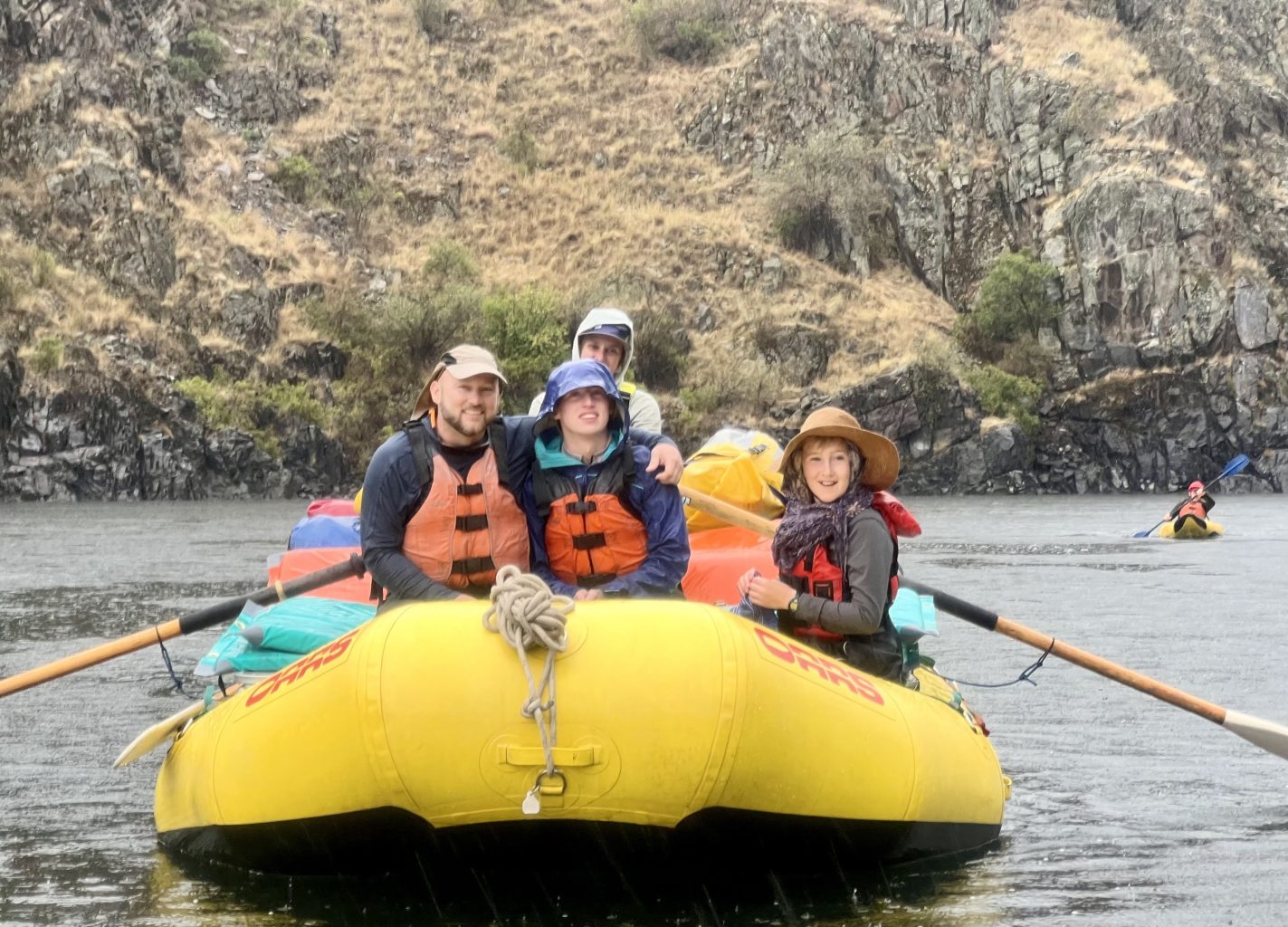 A family sits at the front of a raft on a Snake River rafting trip through Hells Canyon