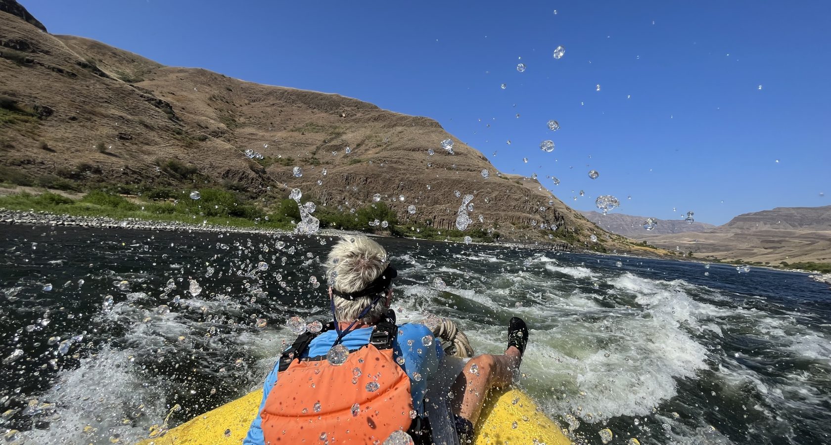 A guest on an OARS rafting trip rides through a rapid on the Snake River